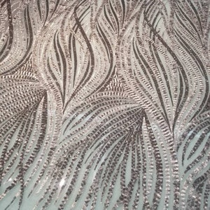 May include: A close-up of a silver and brown sequined fabric with a wavy pattern. The sequins are arranged in a vertical pattern, creating a shimmering effect.