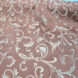May include: A brown fabric with a white damask pattern. The pattern features a repeating design of stylized leaves and vines.