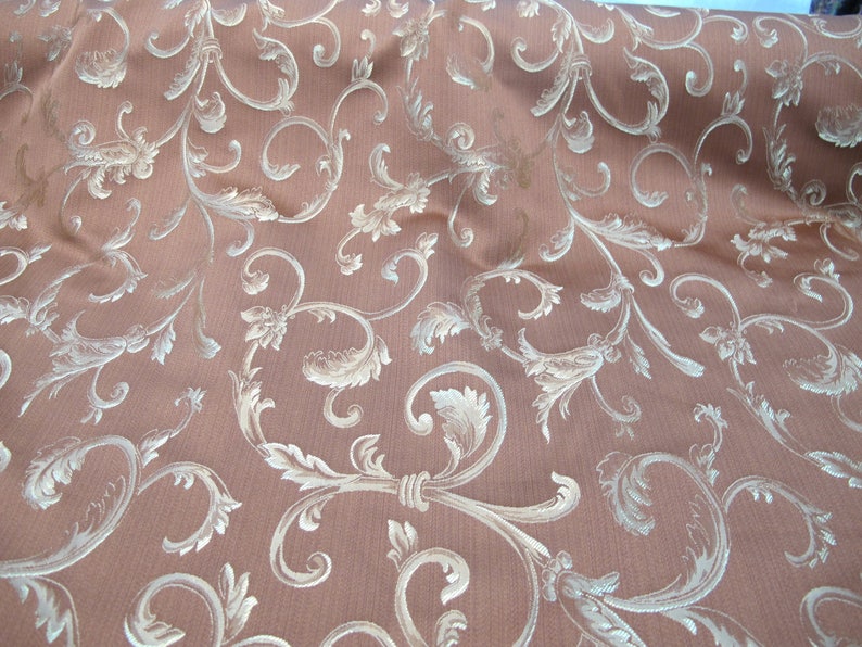 May include: A brown fabric with a white damask pattern. The pattern features a repeating design of stylized leaves and vines.