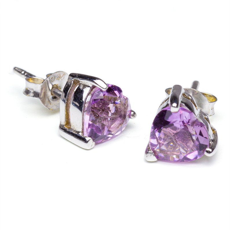 Heart shaped amethyst stud earrings in sterling silver lying on plain white background