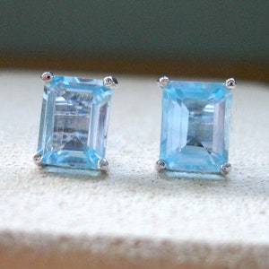 May include: A pair of silver earrings with light blue square-shaped gemstones.