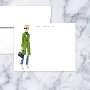 May include: A white card with a green coat illustration and the text "ANNA SMITHSON" printed on it.