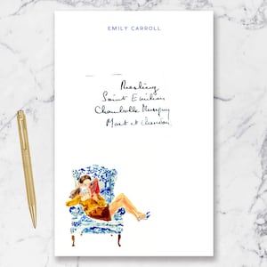 May include: An illustration of a woman reading in a blue and white patterned armchair. The text "Emily Carroll" is at the top, with handwritten wine names below. A gold pen rests on the left.