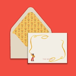 May include: A white card with a gold lasso design and a cartoon cowboy holding a lasso. The card has the text "THE SMITHS" printed on it. The card is in a yellow envelope with a floral pattern.