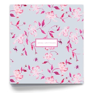 May include: A light blue background with a pink floral pattern. The text "ANNA SMITHSON" is printed in a white rectangle.