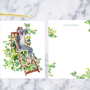 May include: A watercolor illustration of a person sitting on a ladder, surrounded by green foliage, reading a book. The text "ERISHA RUBINOH" is written in blue at the top of the page.