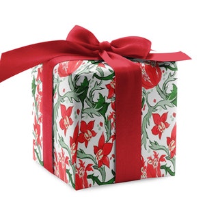 May include: A white gift box with a red ribbon and bow. The box is wrapped in floral patterned paper with red flowers and green leaves.