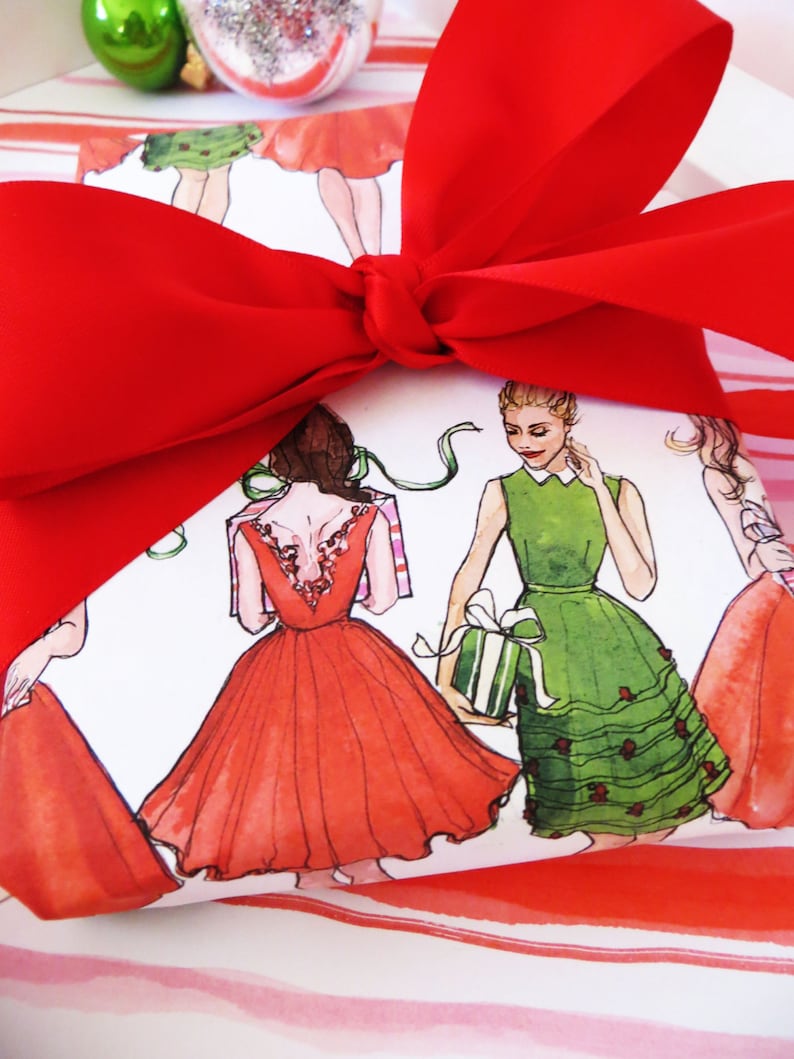Puede incluir: Papel de regalo a rayas rojas y blancas con un lazo rojo. El papel presenta un patr&oacute;n de mujeres con vestidos rojos, verdes y blancos.