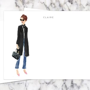 May include: A white card with a black and white illustration of a woman wearing a black coat, sunglasses, and jeans. The text "CLAIRE" is printed at the top of the card.