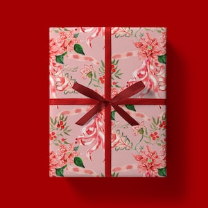 May include: A wrapped gift with a light pink floral patterned paper featuring red poinsettias, green leaves, and red berries. The gift is tied with a dark red ribbon and bow, set against a red background.