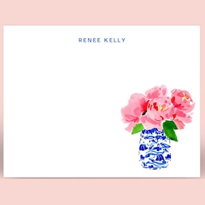 May include: White stationery with a watercolor illustration of pink peonies in a blue and white vase. The text "RENEE KELLY" is printed in navy blue at the top. The design is on a white background with a pink border.