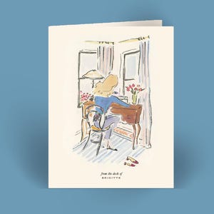 May include: Greeting card with an illustration of a person at a desk, with the text "from the desk of BRIGITTE". The artwork features a desk, chair, window, and flowers. The color palette includes blue, brown, and cream.