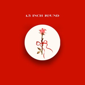 May include: A round, cream-colored sticker with a watercolor illustration of a pink rose tied with a red ribbon. The sticker is 1.5 inches in diameter, set against a bright red background.