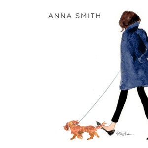 May include: A woman in a blue coat walks with a small brown dog on a leash. The woman is wearing black pants and black shoes. The dog is walking in front of her. The text "ANNA SMITH" is at the top of the image.