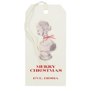 May include: A white gift tag with a watercolor illustration of a bust of a woman with a red bow. The text "Merry Christmas" and "Love, Erish" is printed in red.