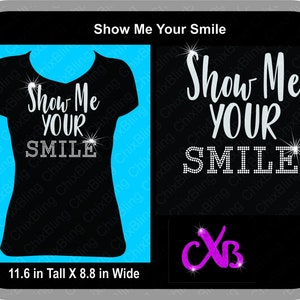 K&ouml;nnte beinhalten: Schwarzes T-Shirt mit silbernen Glitzer-Stra&szlig;steinen, die "Show Me Your Smile" auf einem blauen Hintergrund buchstabieren. Das T-Shirt ist 29,5 cm hoch und 22,4 cm breit.