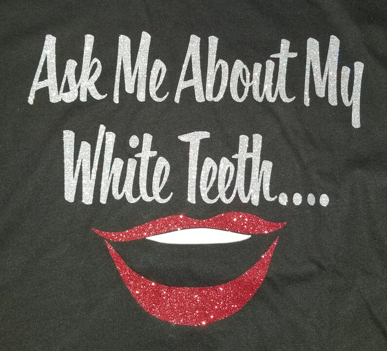K&ouml;nnte beinhalten: Ein schwarzes T-Shirt mit dem Text "Ask Me About My White Teeth..." in silbernen Glitzerbuchstaben. Unter dem Text befindet sich ein roter Glitzermund mit wei&szlig;en Z&auml;hnen.
