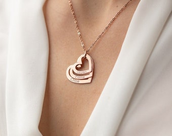 Op de afbeelding: Een ketting van roségoud met drie in elkaar grijpende hartcharms. Elk hart heeft een gegraveerde naam: Hunter, Cole en Lily.