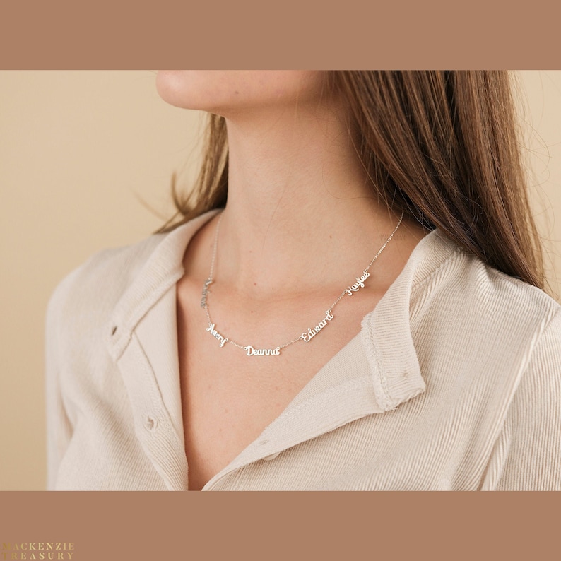 May include: A silver necklace with five names on it: Avery, Deanna, Edward, Kaylee. The necklace is worn by a person with long brown hair.