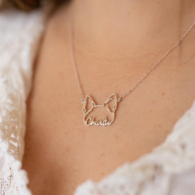 May include: A silver necklace with a dog silhouette pendant. The pendant has the name "Charlie" inscribed inside the silhouette.