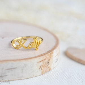 May include: Gold ring with the name "Kelly" written in cursive script.