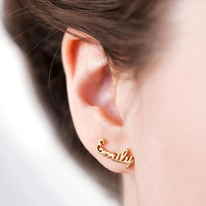 May include: Gold earrings with the name "Emily" written in a cursive script.