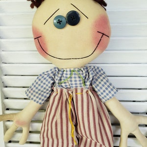 May include: A handmade rag doll with brown yarn hair, blue and green button eyes, a red and white striped skirt, and a blue and white checkered shirt.