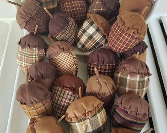 May include: A collection of brown and tan fabric acorns with plaid and patterned designs. The acorns are handmade and have a rustic, farmhouse style.