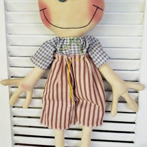 May include: A handmade rag doll with brown yarn hair, blue eyes, and a red and white striped outfit. The doll is smiling and has rosy cheeks.