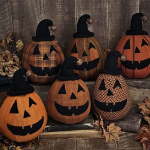 May include: A collection of six handcrafted pumpkin decorations with black witch hats and carved jack-o'-lantern faces. The pumpkins are orange and patterned with black fabric. A rustic, fall-themed display.