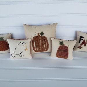 May include: Five small decorative pillows with fall-themed embroidery. The pillows feature a bird, pumpkins, and the word "FALL".