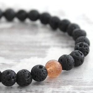 May include: A black lava rock bracelet with a single orange sunstone bead.