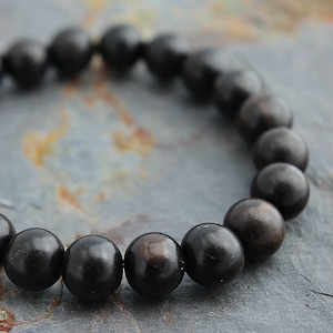 May include: A black wooden beaded bracelet with round beads.