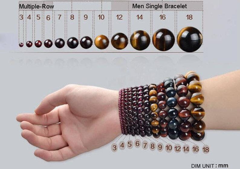 Puede incluir: Un conjunto de pulseras de piedra de ojo de tigre de diferentes tama&ntilde;os, que van de 3 a 18 mm de di&aacute;metro. Las pulseras se muestran en la mu&ntilde;eca de una persona, con las cuentas dispuestas en una sola fila.