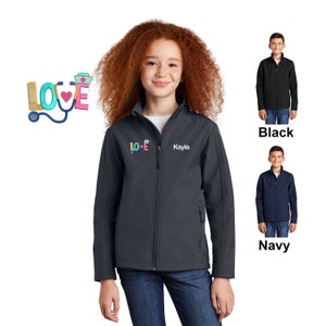 May include: A dark blue youth-sized soft-shell jacket with a zipper closure. The jacket has a  "LOVE" graphic with a stethoscope and medical symbols. The name "Kayla" is embroidered on the jacket. The jacket is shown on a model wearing blue jeans.