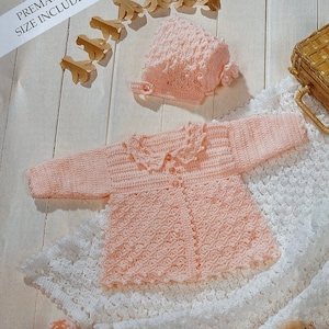 May include: A pink crocheted baby jacket with a white crocheted collar, a matching pink crocheted hat, and a white crocheted blanket. The set is designed for premature babies.