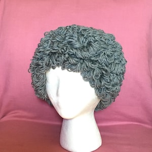 May include: Gray crocheted hat with a curly texture, displayed on a mannequin head.