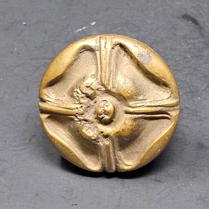 May include: A round, gold-colored metal button with a raised, four-pointed star design.