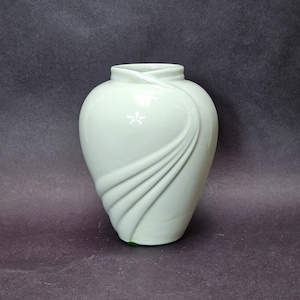May include: A white ceramic vase with a unique, flowing design. The vase has a smooth, glossy finish and a rounded shape.