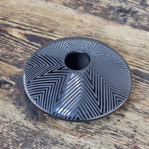 May include: Black ceramic vase with a geometric pattern. The vase is round and has a wide opening at the top.