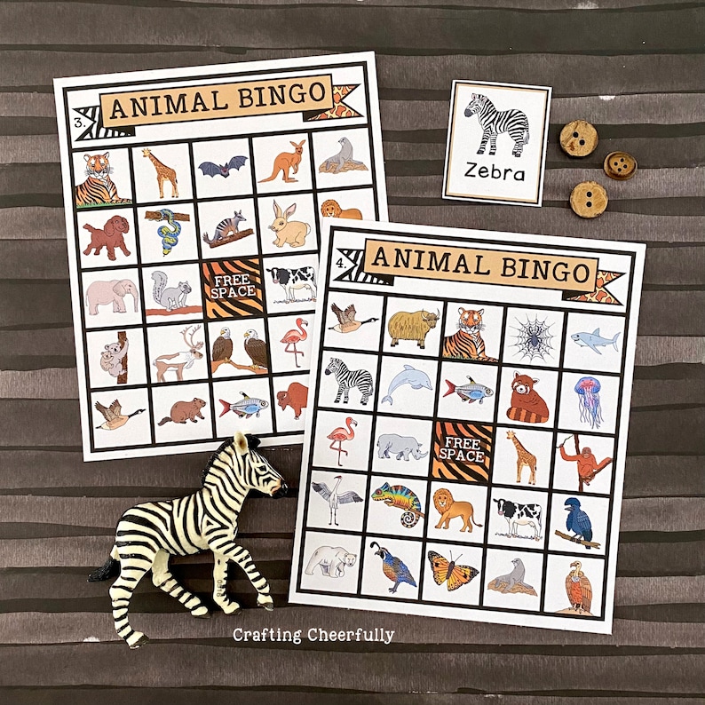 May include: Two printable animal bingo cards featuring a zebra, tiger, giraffe, elephant, flamingo, spider, and other animals. The cards are on a brown striped background with a zebra figurine and buttons.