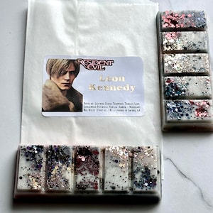 Puede incluir: Una barra de cera blanca con cuatro secciones, cada una con un patr&oacute;n de purpurina diferente. La barra est&aacute; etiquetada como "Resident Evil Leon Kennedy" con notas de cuero, cedro, teca, hoja de tabaco, s&aacute;ndalo, pachul&iacute;, vainilla, &aacute;mbar y marogant. Las ceras para fundir son de 3 oz netos o 85 g y se vierten en Smyrna, GA.