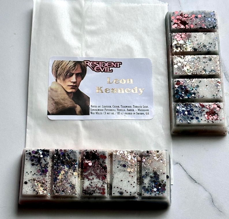 Puede incluir: Una barra de cera blanca con cuatro secciones, cada una con un patr&oacute;n de purpurina diferente. La barra est&aacute; etiquetada como "Resident Evil Leon Kennedy" con notas de cuero, cedro, teca, hoja de tabaco, s&aacute;ndalo, pachul&iacute;, vainilla, &aacute;mbar y marogant. Las ceras para fundir son de 3 oz netos o 85 g y se vierten en Smyrna, GA.