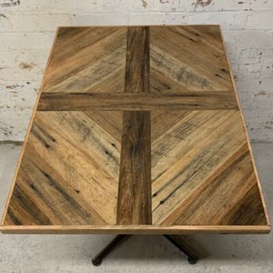 May include: A square wooden table top with a chevron pattern in shades of brown. The table top is made of reclaimed wood and has a rustic look.