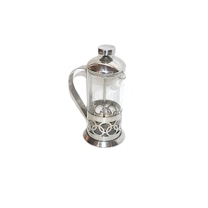 Peut inclure: Une cafetière à piston cylindrique dotée d'une carafe en verre transparent insérée dans une structure en acier inoxydable poli avec un motif décoratif de cercles entrelacés, un couvercle métallique assorti, un piston et une poignée latérale.
