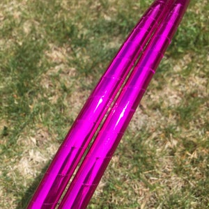 May include: Two pink metallic hula hoops stacked together. The hoops are shiny and reflect light.