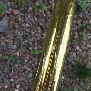 May include: Two gold-coloured hula hoops with a reflective finish. The hoops are made of plastic and have a textured surface.