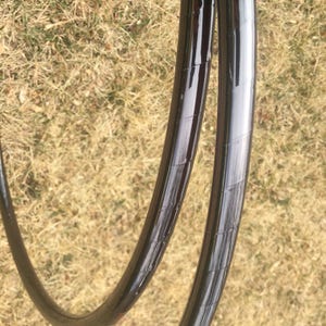 May include: Two black plastic hula hoops with a shiny finish. The hoops are stacked on top of each other.