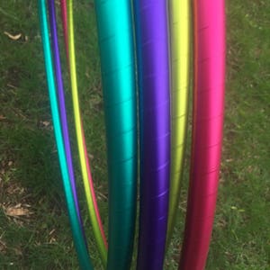 May include: Four colourful hoops, each with a different metallic finish: teal, purple, yellow and pink. The hoops are stacked together, with the teal hoop on top and the pink hoop on the bottom.