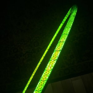 May include: A green and yellow reflective hula hoop with a geometric pattern.